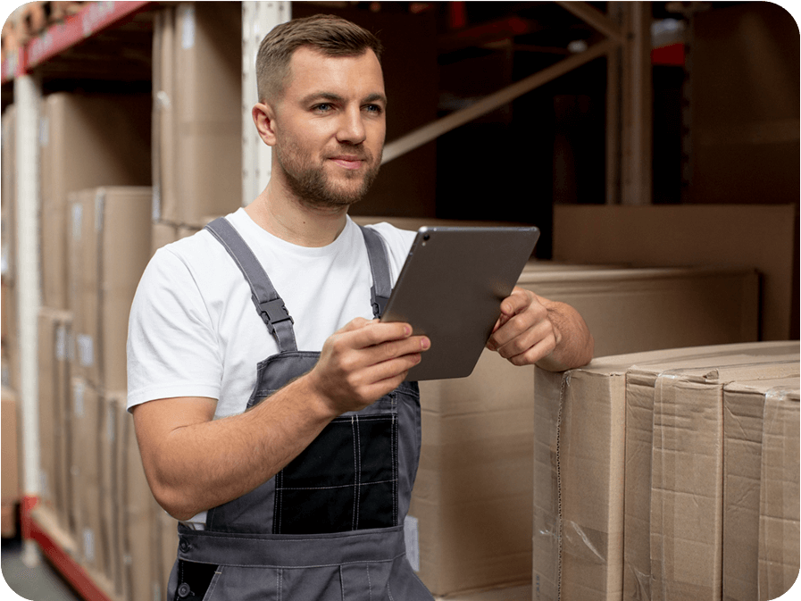Professional warehouse worker in safety overalls using tablet for inventory management and stock control in modern distribution center