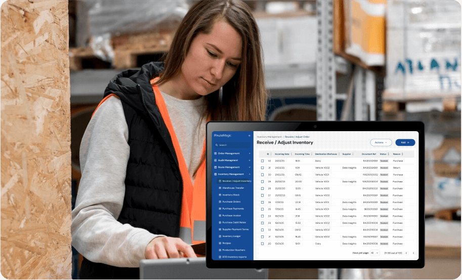 Warehouse staff member in safety gear using laptop for real-time inventory management and stock control